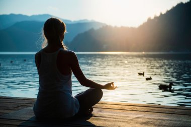 woman meditating on lake shore clipart