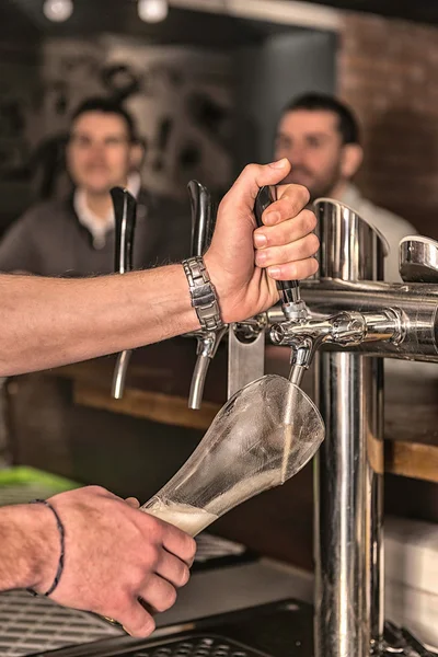 Bartender drawing beer in pub — Stock Photo, Image