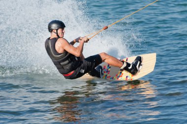 man riding wakeboard at high speed clipart