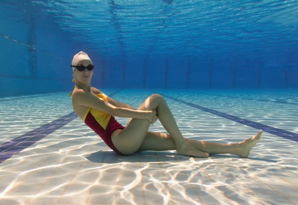 Woman sitting at swimming pool bottom — Stock Photo, Image