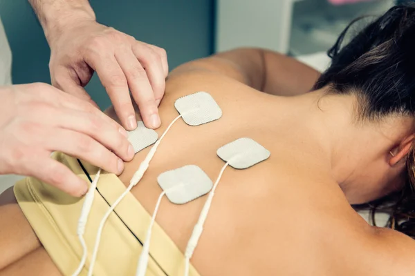 Eletrodos de posicionamento do terapeuta nas costas do paciente — Fotografia de Stock