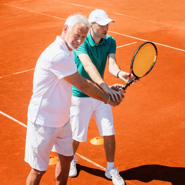 Äldre man med tennis instruktör — Stockfoto