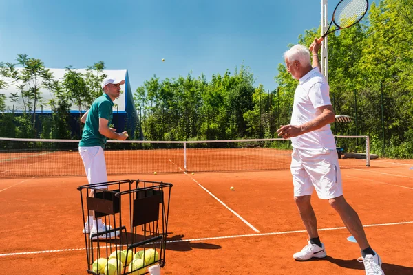 Senior activo con instructor de tenis — Foto de Stock