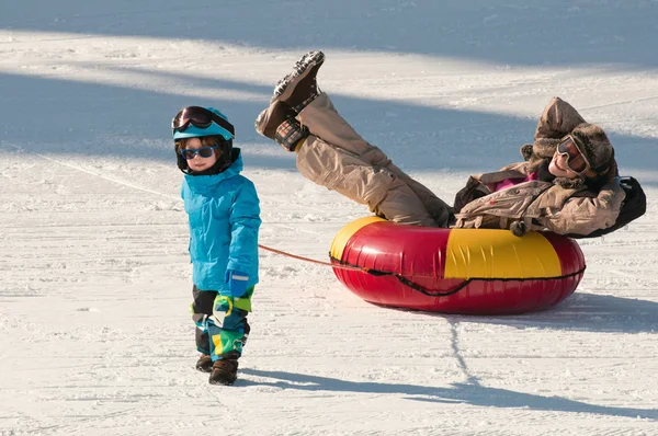 Boy pulling snowtube with mom on — Stock Photo, Image