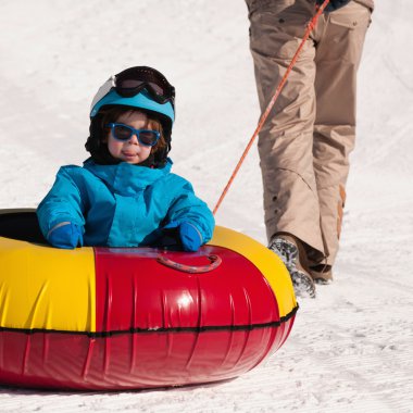 boy enjoying ride in snow tube clipart