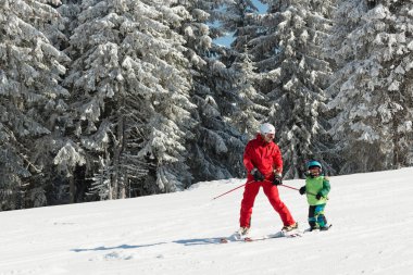 Skiing instructor working with boy clipart