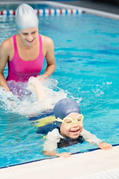 Instructor y niño pequeño pateando en la piscina — Foto de Stock