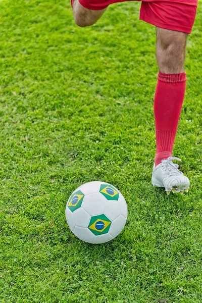 Atacador de futebol chutando bola — Fotografia de Stock