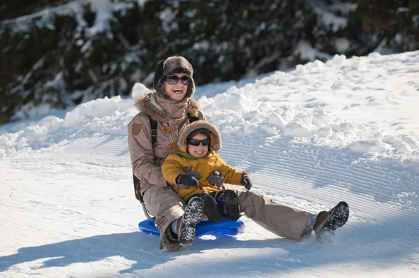 Ibu dan anak menikmati salju sledging — Stok Foto