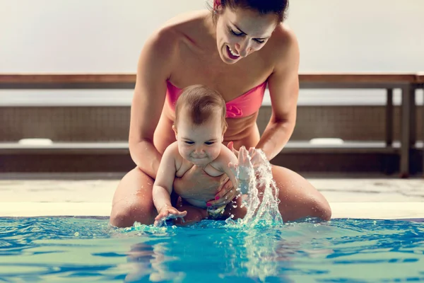 Mãe com seu filho sentado na borda da piscina — Fotografia de Stock