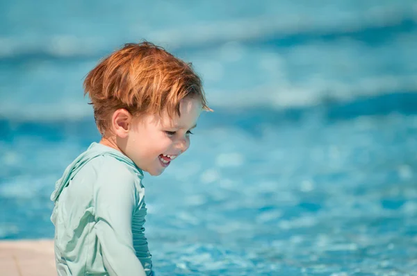 Boy in rashguard sitting on pool edge — Stock Photo, Image