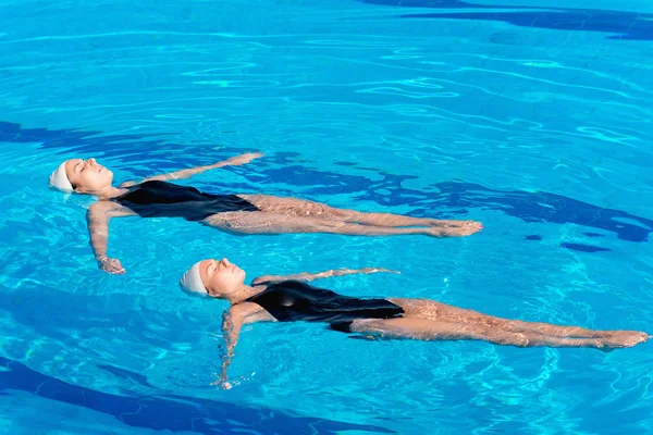 Synchronized swimmers duet floating on water — Stock Photo, Image