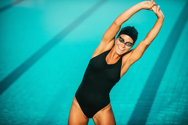 Lächelnde Schwimmerin streckt sich — Stockfoto