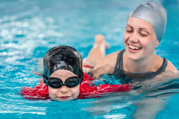 Child in swimming pool with instructor — Stock Photo, Image