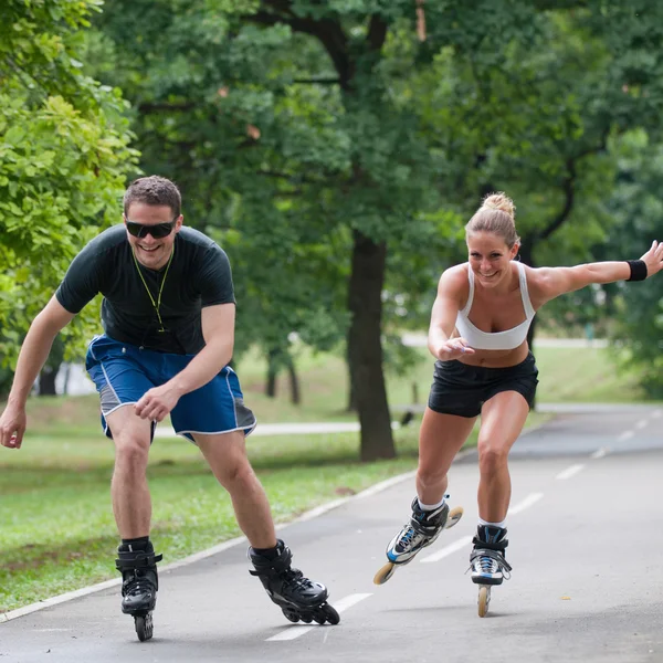 Pareja patinaje sobre ruedas a través del parque — Foto de Stock