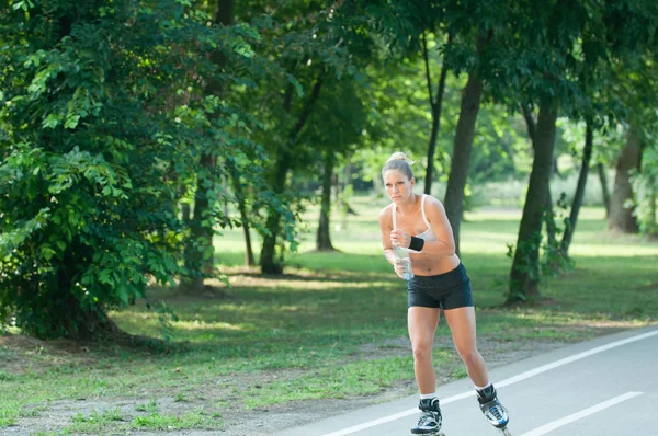 Mujer patinaje sobre ruedas a través del parque — Foto de Stock