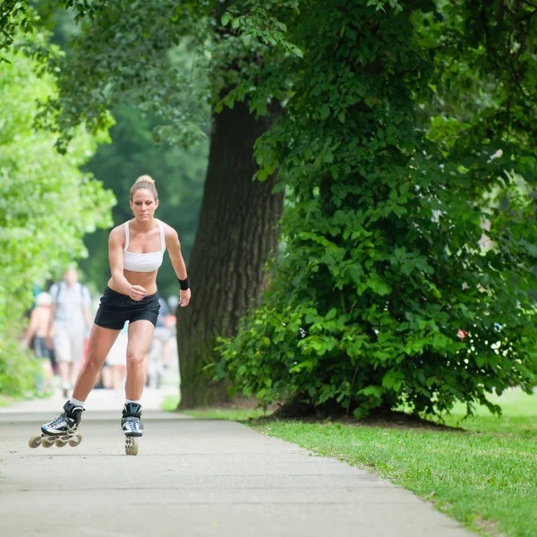 Patin à roulettes femme à travers le parc — Photo