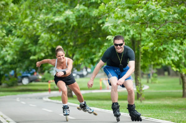 Pareja patinaje sobre ruedas a través del parque — Foto de Stock