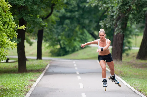 Mujer patinaje sobre ruedas a través del parque — Foto de Stock