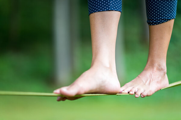 female legs balancing barefoot on Slackline