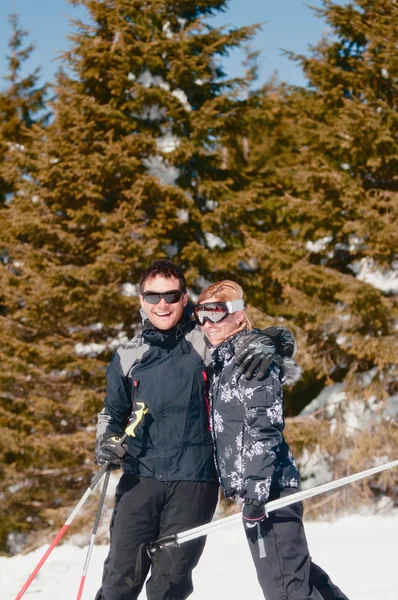 Casal segurando bastões de esqui e olhando para a câmera — Fotografia de Stock