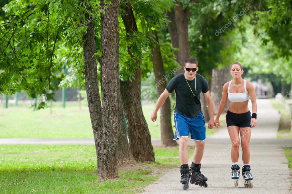 Couple roller skating through park — Stock Photo © microgen 115192628
