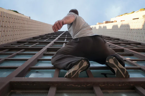 Hombre escalada edificio desde el exterior — Foto de Stock