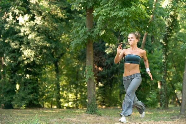 Ung kvinna joggar i parken — Stockfoto