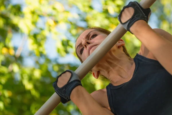 Feminino fazendo pull ups na barra de puxar para cima — Fotografia de Stock