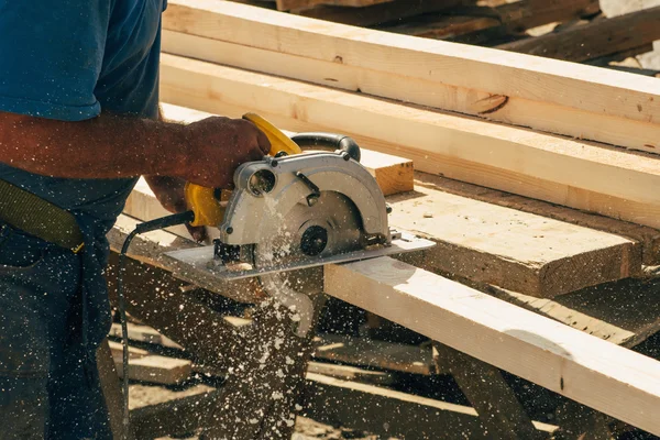 Construction worker cutting wooden beam — Stock Photo, Image