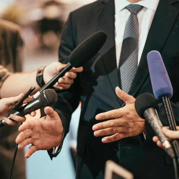 Media microphones surrounding politician — Stock Photo, Image