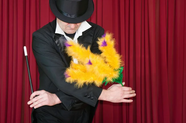 Magician with yellow flowers on stage — Stock Photo, Image