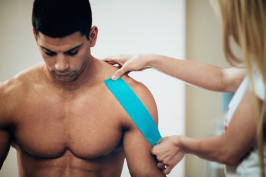 therapist placing kinesio tape on shoulder clipart