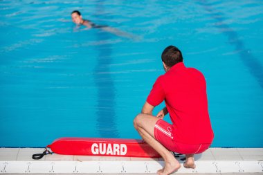 Lifeguard sitting at poolside clipart