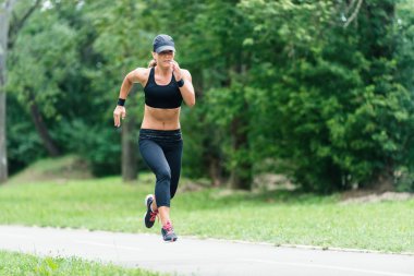 Genç bayan parkta koşuyor.