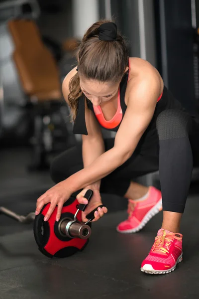 Female athlete setting up barbell weights — Stock Photo, Image