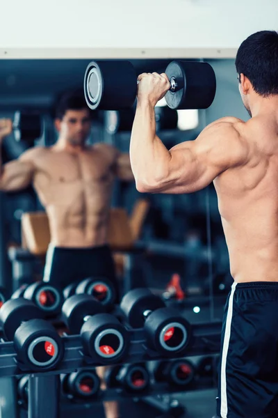 Body building champion exercising in front of mirror — Stock Photo, Image