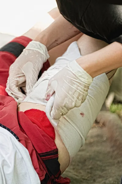Procedimento de primeiros socorros com perna ferida — Fotografia de Stock