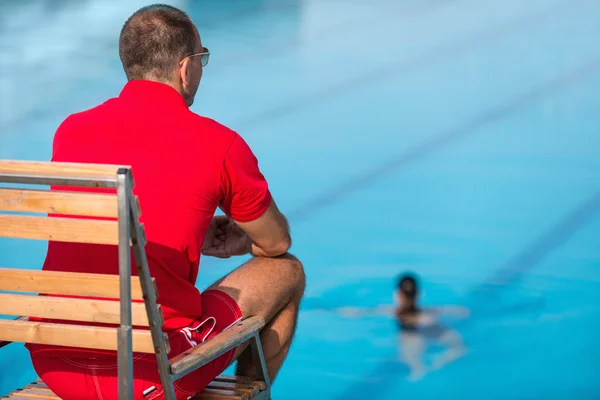 Salva-vidas sentado na cadeira acima da piscina — Fotografia de Stock