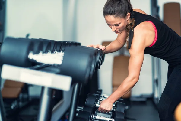 Woman picking up dumbbell — Stock Photo, Image