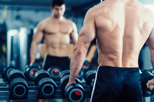 Muscular young man exercising in gym — Stock Photo, Image