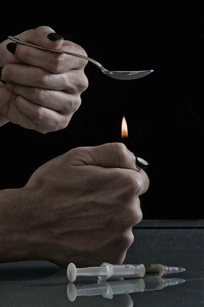 Человек, нагревающий героин в ложке
