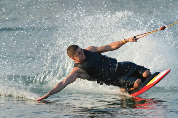 Man kneeboarding and touching water surface — Stock Photo, Image