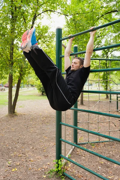 Male athlete exercising on stall bars — Stock Photo, Image