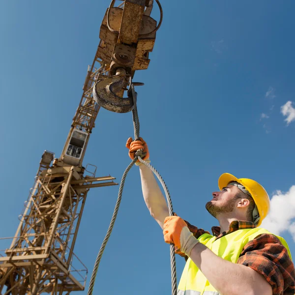 Construction worker hooking cable to crane — Stock Photo, Image