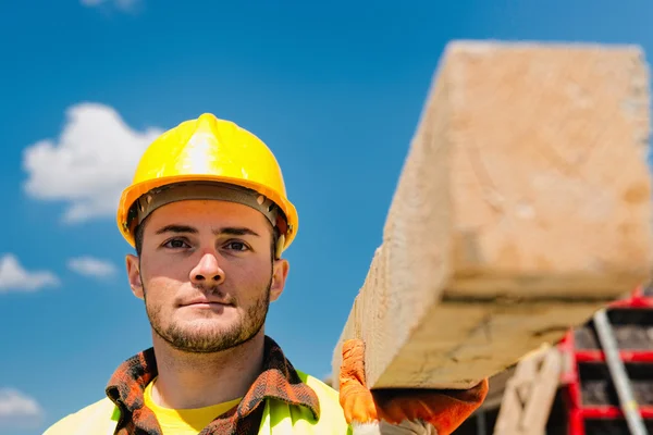 Trabalhador da construção com viga de madeira — Fotografia de Stock