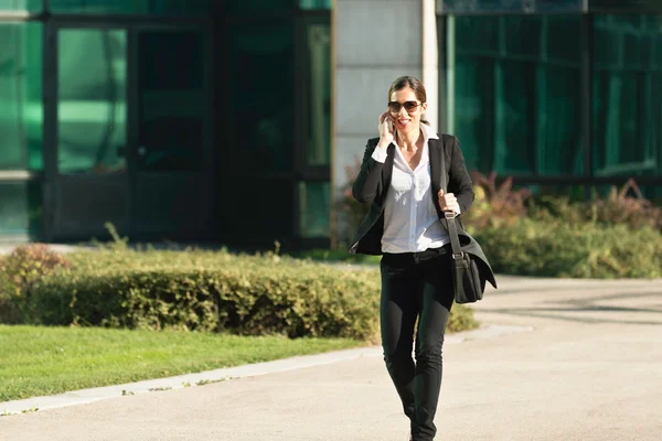 Affärskvinna promenader och med mobiltelefon — Stockfoto
