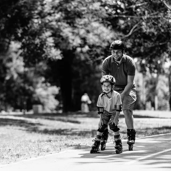 Otec na kolečkových bruslích v parku se synem — Stock fotografie