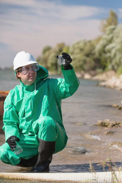 Environmentalist looking at sample of polluted water — Stock Photo, Image