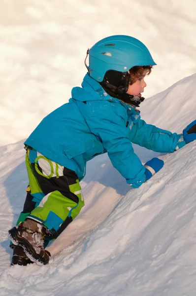 Petit garçon grimpant sur la neige — Photo